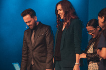 pastor and family praying on stage during a worship service 