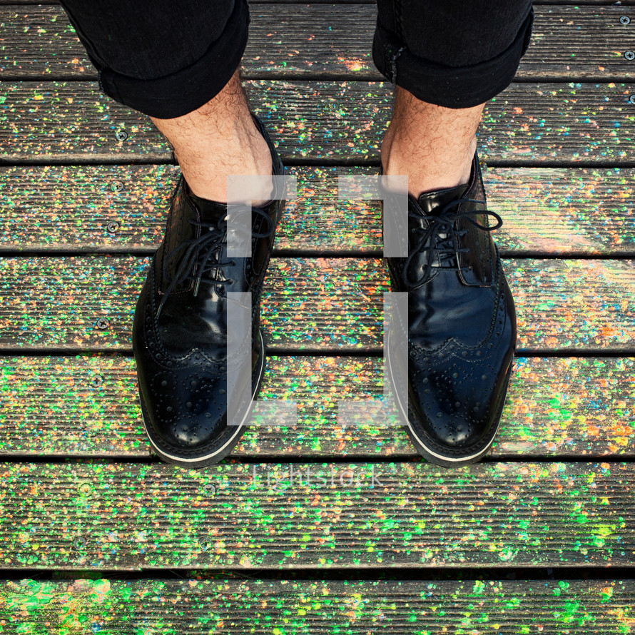 Close up of feet with polished shoes on colored powder