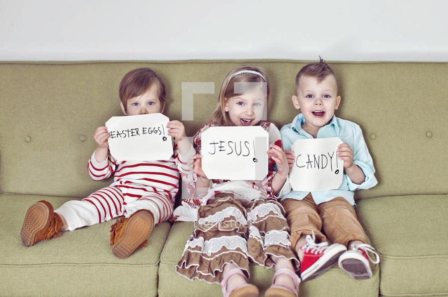 children sitting on a couch holding Easter signs 