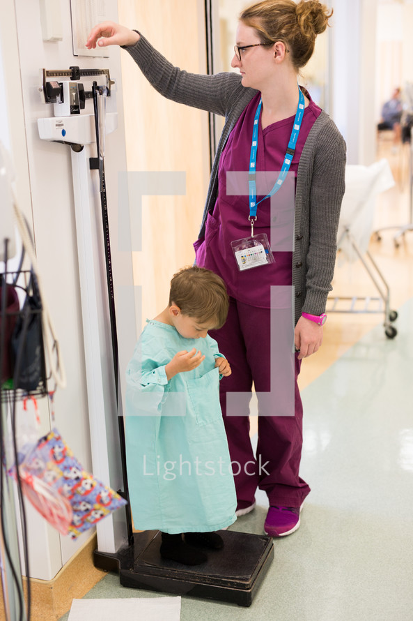 a nurse weighing a boy child in a hospital gown 