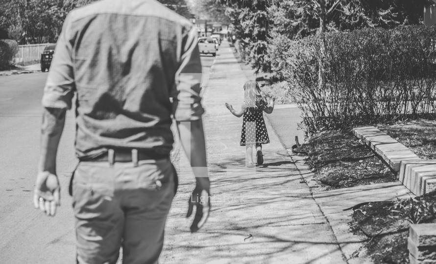 father and daughter walking down a sidewalk 