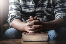 man with praying hands over a Bible 