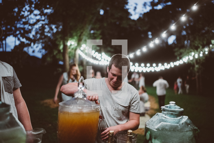 people gathered for an outdoors dinner party pouring drinks 