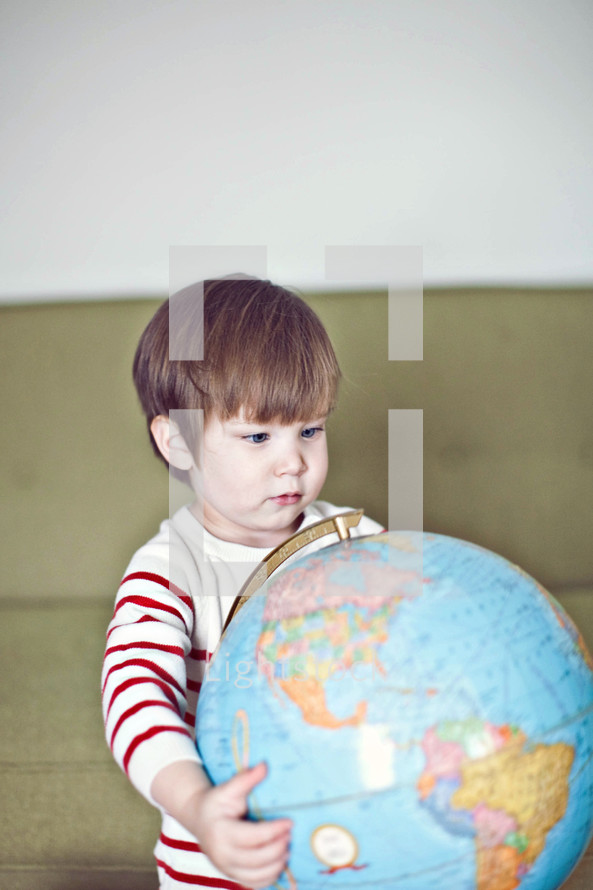 a toddler holding a globe 