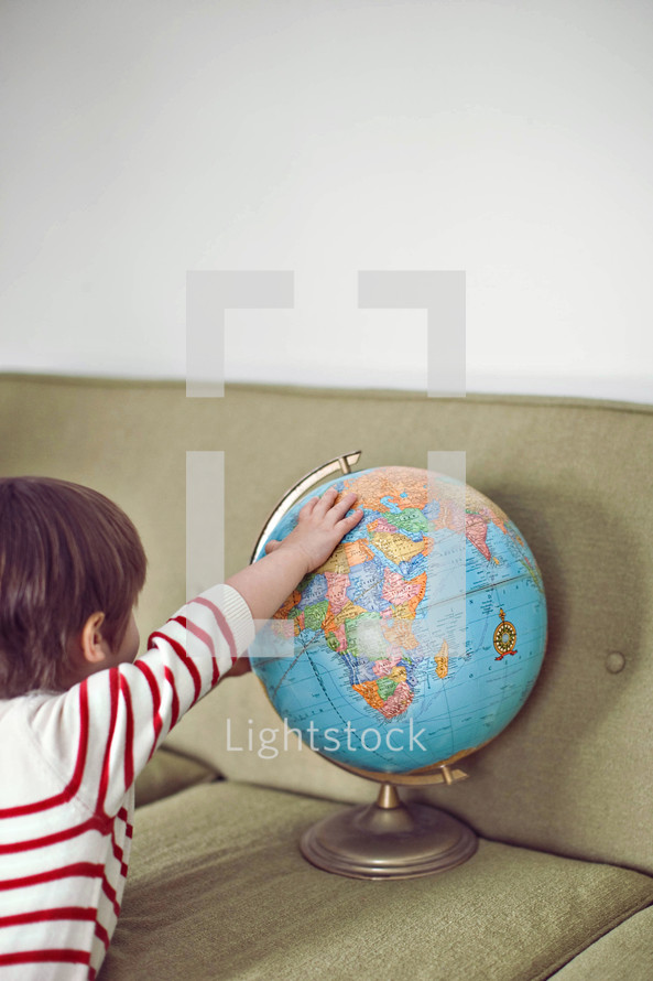 boy toddler touching a globe 