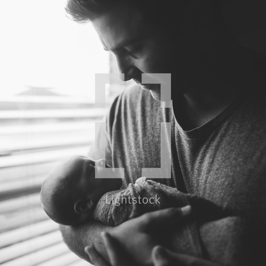 father holding a swaddled newborn 