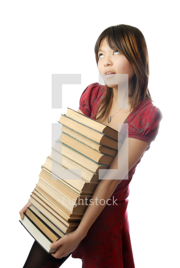 Young schoolgirl carrying numerous heavy books
