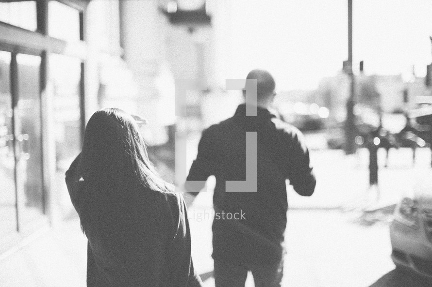 A man and woman walking down the sidewalk