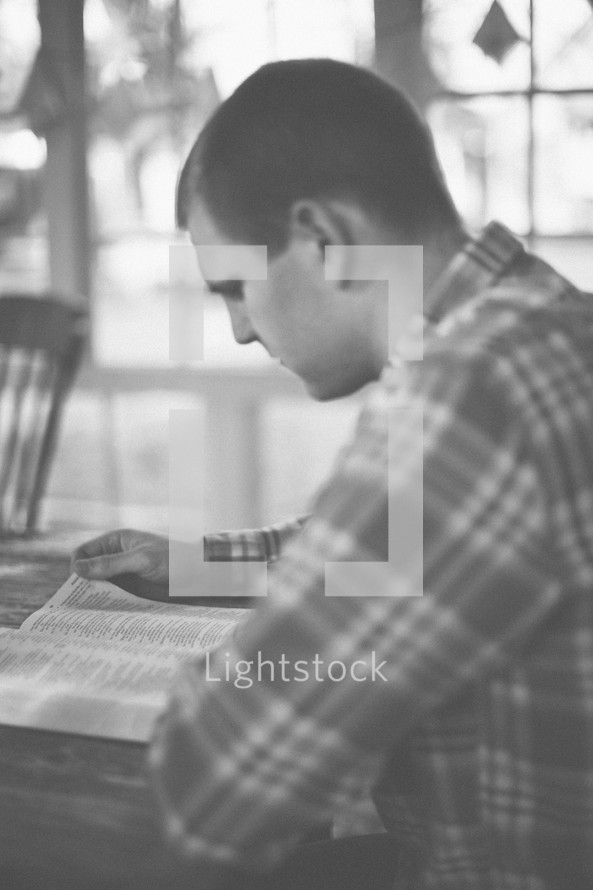 A man sitting at a table reading the Bible