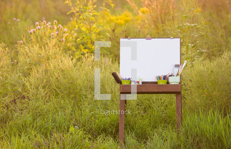 easel, art supplies, and a blank canvas outside 