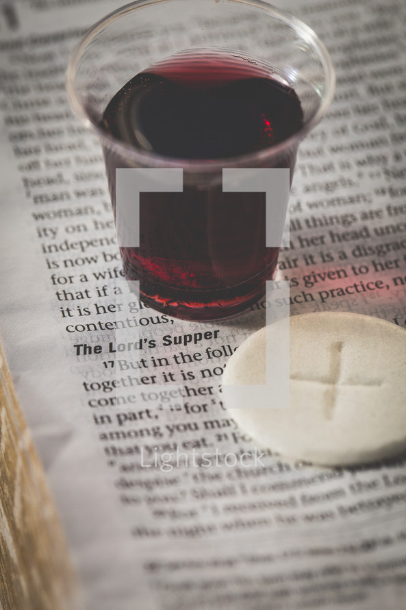 communion cup and wafer on the pages of a Bible 