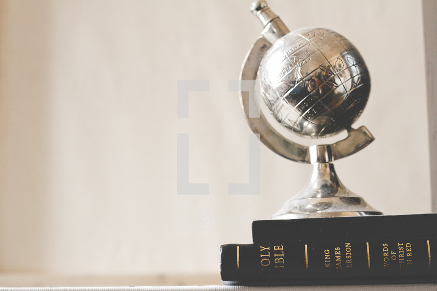 brass globe paper weight on a stack of books 