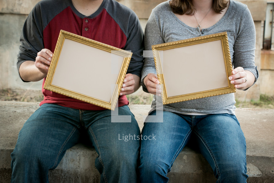 couple holding empty frames 