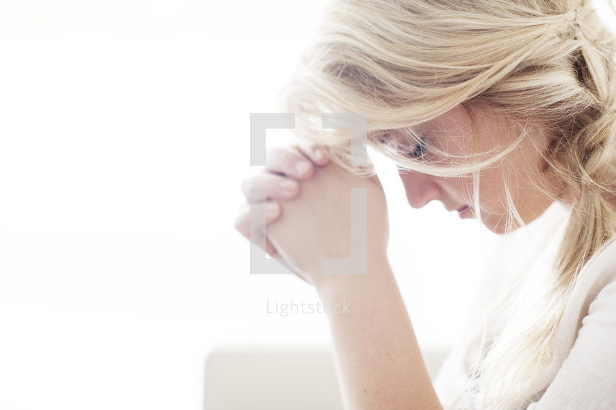 woman alone with head bowed and praying hands 