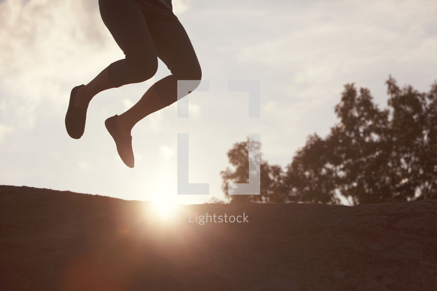 woman jumping on top of rock at sunset