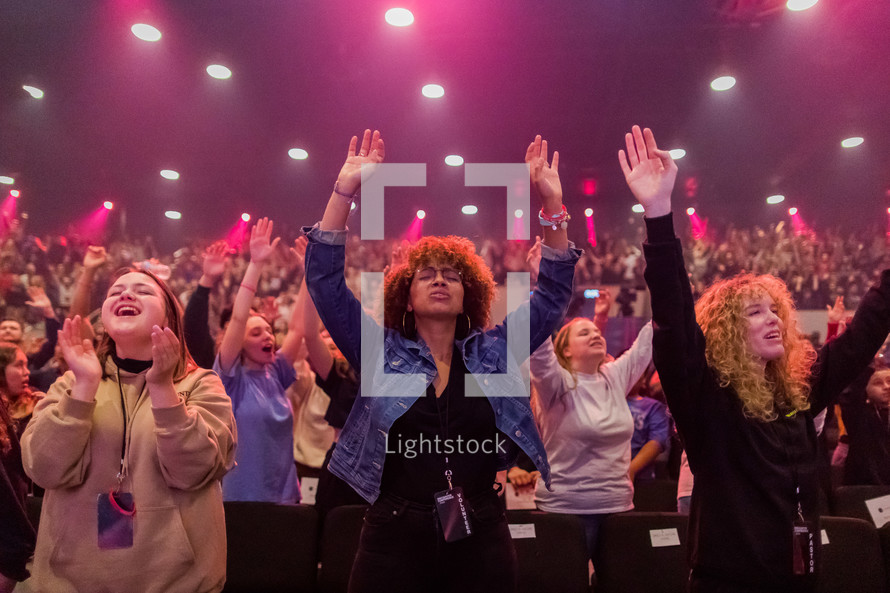 women with hands raised in praise during a worship service 