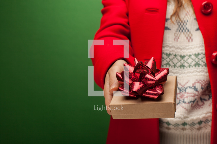 a woman in a red peacoat holding a Christmas gift box 