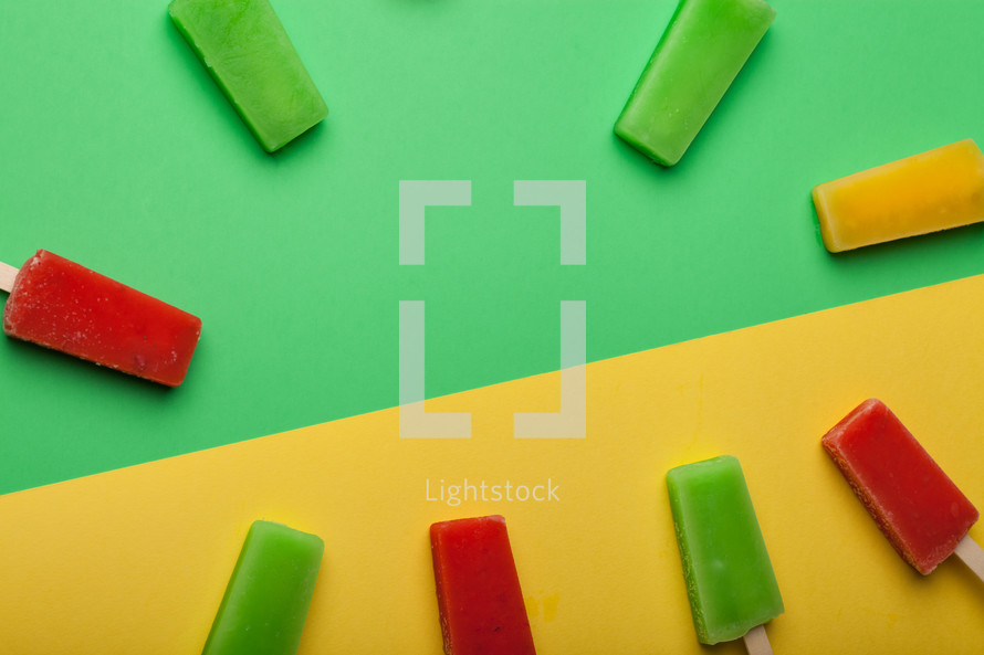 Brightly colored popsicles in a circle on a green and yellow background.