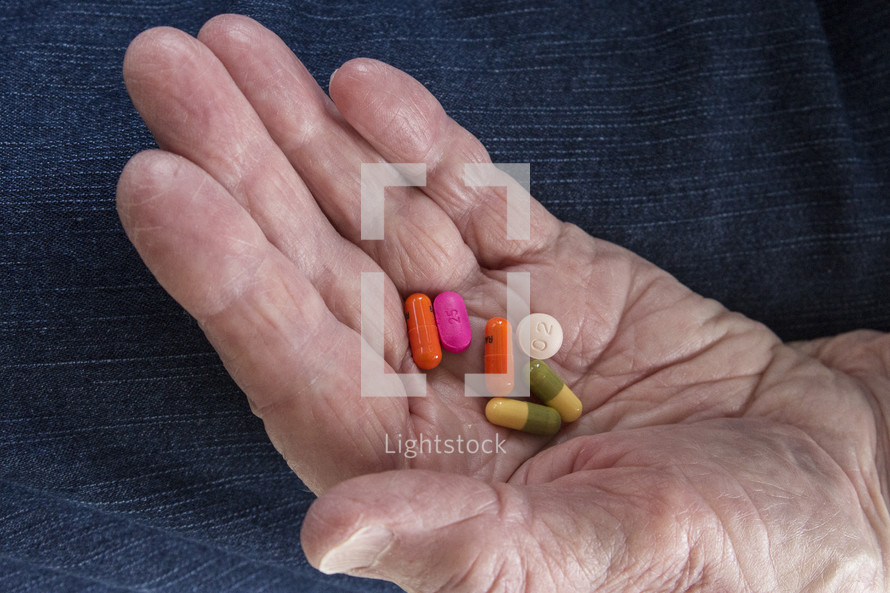 pills in the hand of an elderly woman