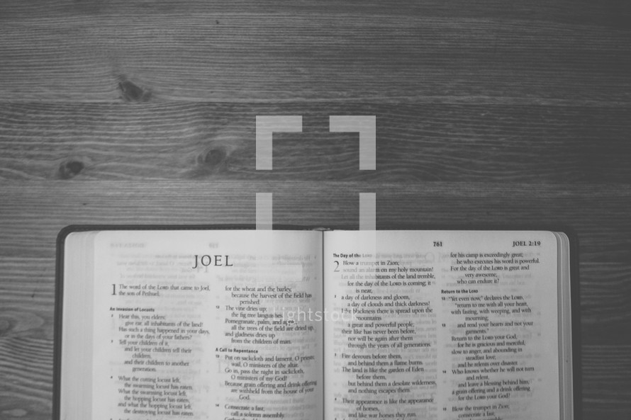 Bible on a wooden table open to the book of Joel.