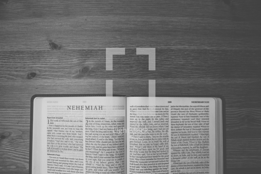 Bible on a wooden table open to the book of Nehemiah.