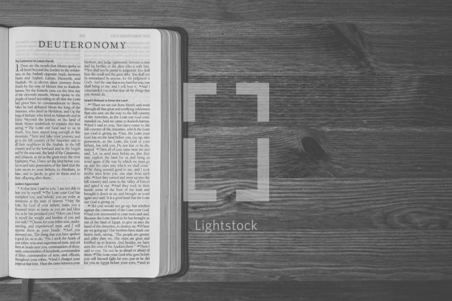 Bible on a wooden table open to the book of Deuteronomy.