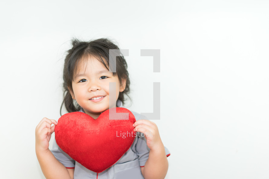 toddler girl holding a red heart 