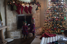 girls standing under a mantel by a decorated Christmas tree 