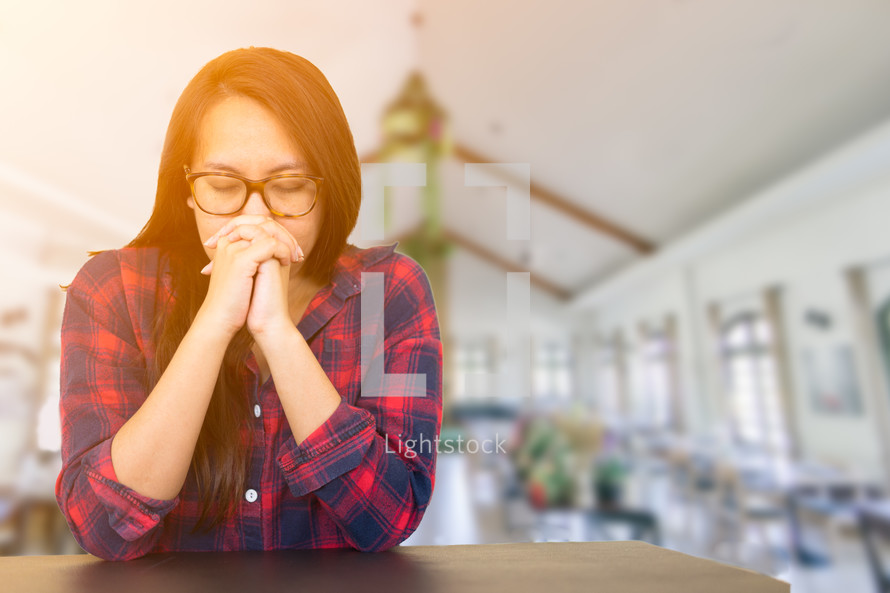 a woman praying at a table 