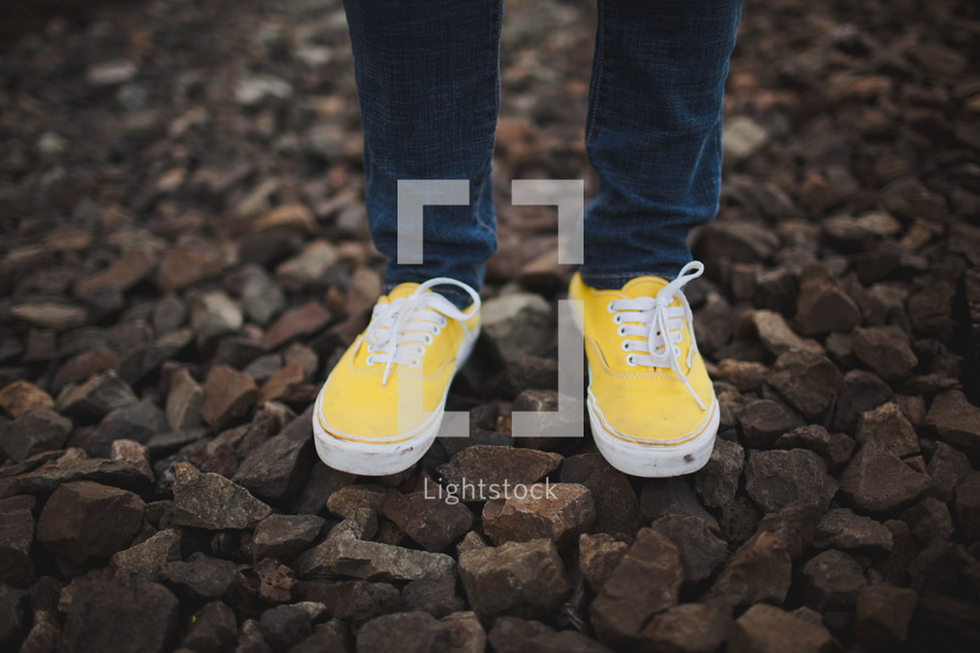 yellow sneakers standing on the gravel