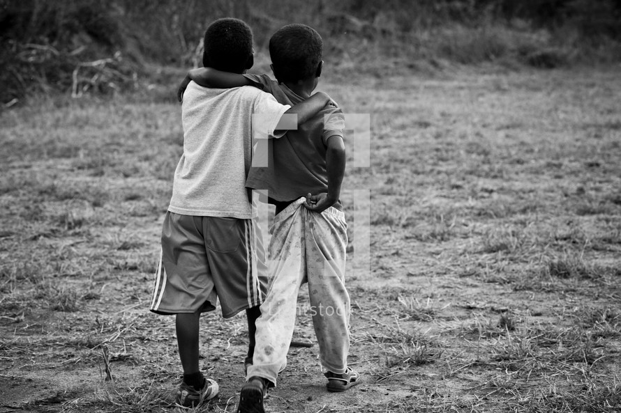 Two young boys walking together with their arms around each other