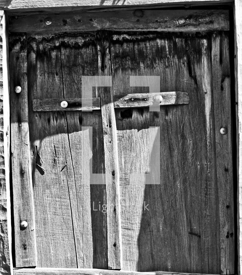 Wooden cross nailed to wooden door