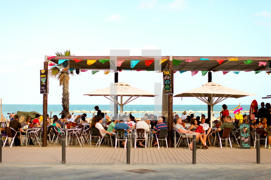 A crowd eats on the patio near the beach in Barcelona