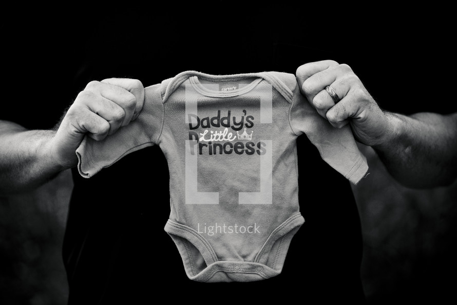 closeup of a father holding a onesie with the words DADDY'S LITTLE PRINCESS