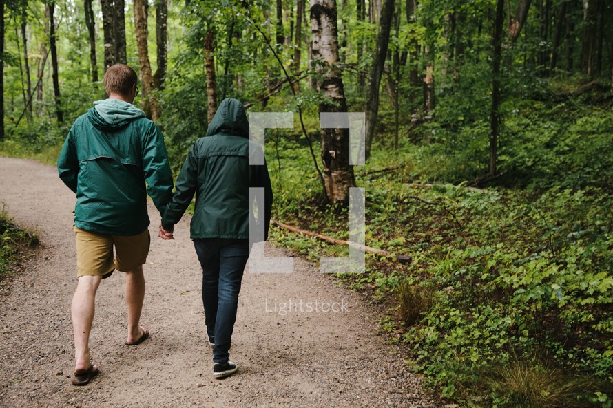 a couple holding hands walking on a nature trail 