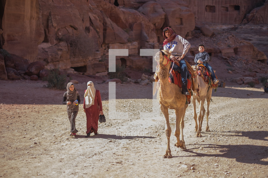 people riding on camels in a desert 