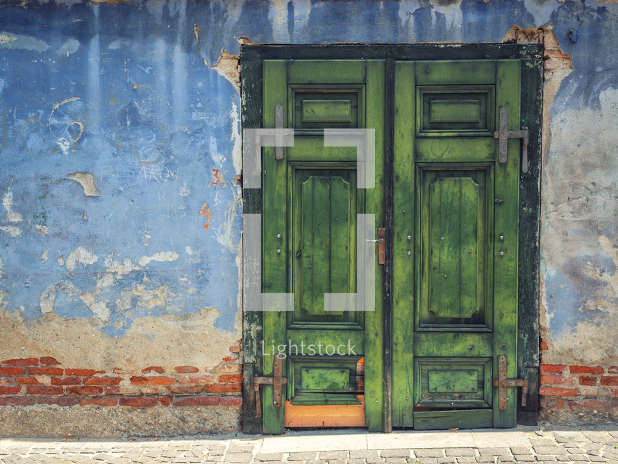 Green wooden door in an old blue building