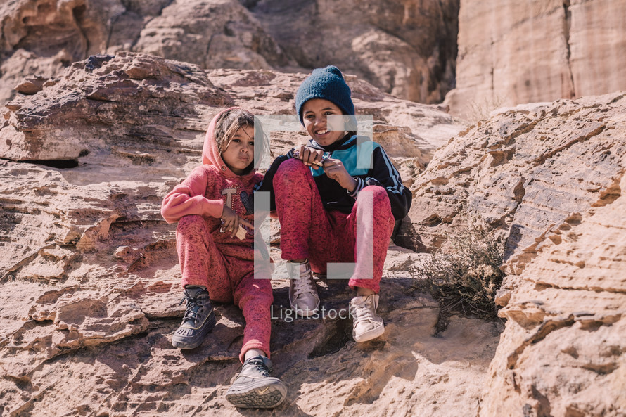 little girls sitting in a desert 