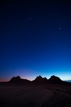 stars in the night sky over desert mountain peaks 