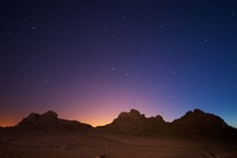 stars in the night sky over mountain peaks 