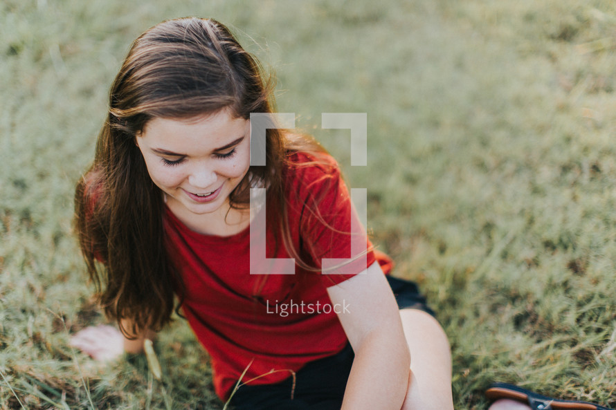teen girl sitting in a field 