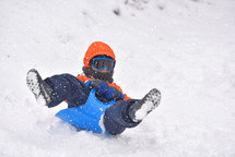 child sledding in snow 