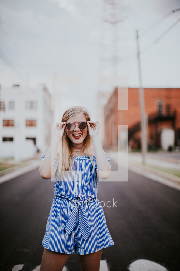 teen girl in a romper standing in the middle of a road 