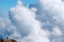 man standing at the edge of a cliff in the clouds 