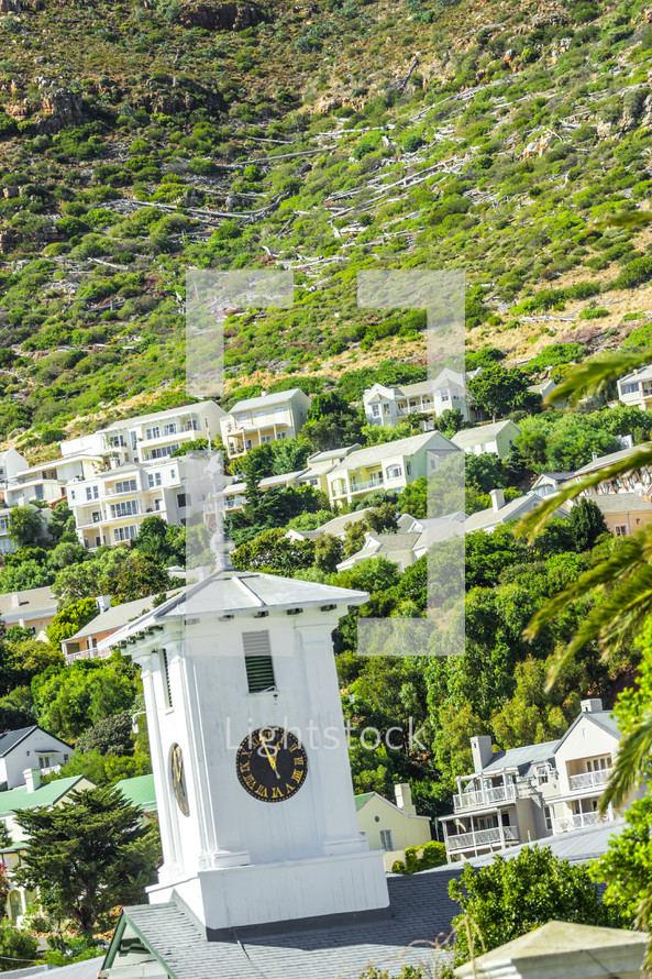 Clock tower and homes on a steep hillside. 