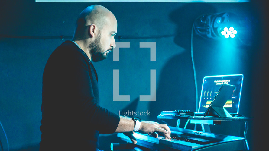 a man on stage playing a digital keyboard 