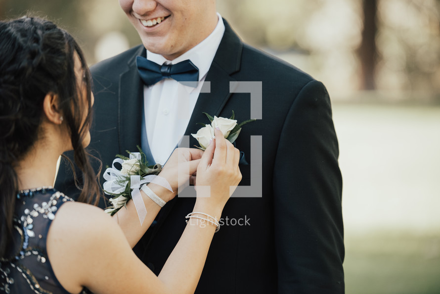 a teen girl putting on a boutonniere