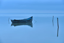 Lonely boat on big lake in the fog, blue hour before sunrise