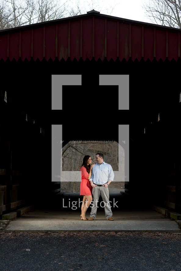 man and woman standing under a covered bridge 
