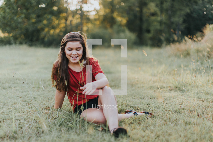 teen girl sitting in a field of grass